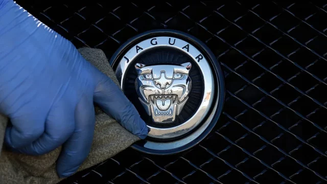 Foto arsip pekerja memoles logo Jaguar pada sebuah mobil di diler Jaguar di London