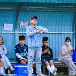 Pelatih dan sejumlah pemain sepak bola berada di pinggir lapangan