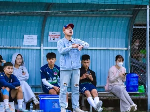 Pelatih dan sejumlah pemain sepak bola berada di pinggir lapangan
