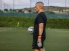 Seorang pelatih memegang bola sepak di lapangan latihan berumput