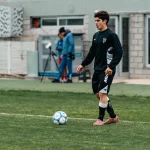 Seorang pemain sepak bola berlatih mengolah bola di lapangan berumput