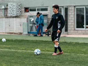 Seorang pemain sepak bola berlatih mengolah bola di lapangan berumput
