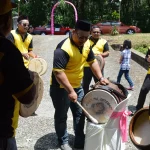 Beberapa laki-laki berseragam kuning hitam memukul kompang dan sebuah bass drum di jalan