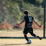 Pemain sepak bola menendang bola dalam pertandingan