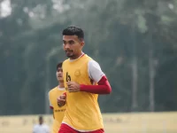 Pemain sepak bola berompi kuning berlari dalam sesi latihan di lapangan