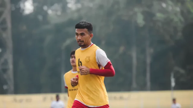 Pemain sepak bola berompi kuning berlari dalam sesi latihan di lapangan