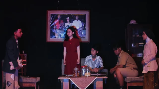 Lima aktor dalam satu adegan pementasan teater di panggung berlatar ruang tamu yang gelap