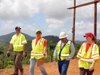 Petugas berompi keselamatan meninjau pemulihan jaringan listrik dengan tiang baru di Puerto Rico