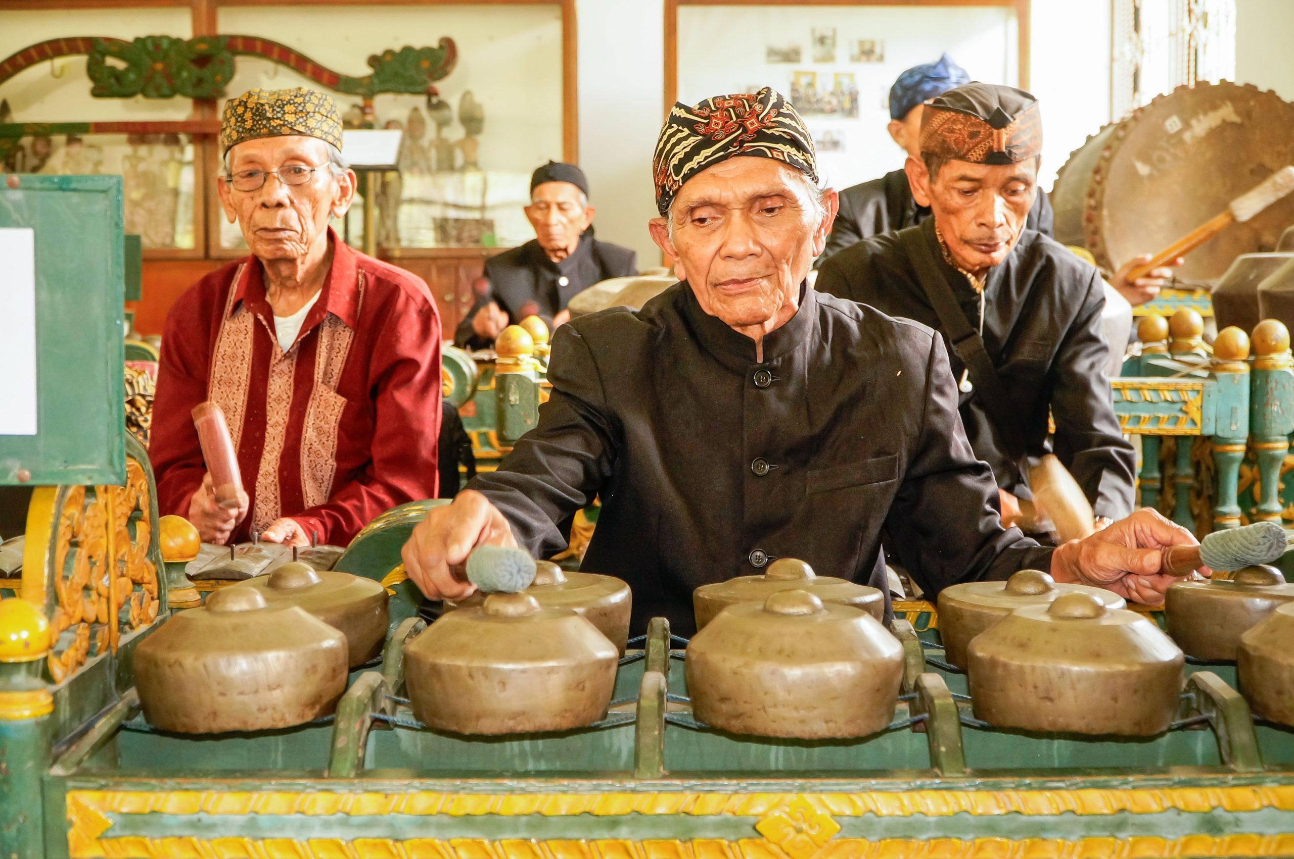 Ilustrasi sekelompok musisi lanjut usia memainkan gamelan berjajar.