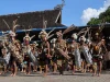Penari laki-laki Dayak Kenyah berhiasan bulu dan tameng ukir di halaman lamin adat