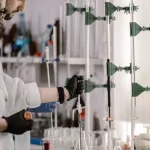 Dua peneliti berjas laboratorium bekerja dengan tabung reaksi
