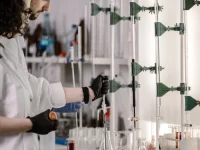 Dua peneliti berjas laboratorium bekerja dengan tabung reaksi