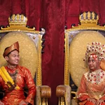 Sepasang pengantin mengenakan pakaian adat Melayu Deli lengkap dengan tutup kepala
