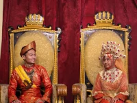 Sepasang pengantin mengenakan pakaian adat Melayu Deli lengkap dengan tutup kepala