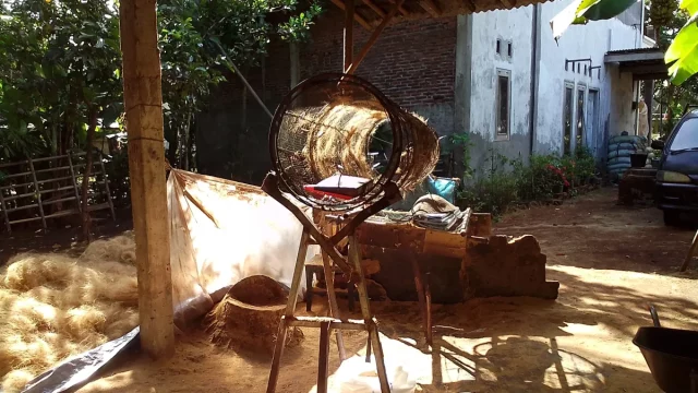 Mesin dan tumpukan sabut kelapa diolah menjadi serat di halaman rumah warga