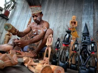 Pengukir kayu Asmat sedang memahat patung kayu tradisional
