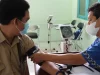 Petugas kesehatan bermasker mengukur tekanan darah pasien dengan tensimeter di ruang klinik, Indonesia