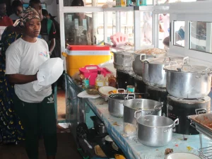 Penjual perempuan berbandana di balik deretan panci berisi masakan di warung makan Ghana