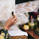 Ilustrasi perajin membatik kain dengan canting di Yogyakarta