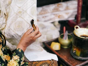 Ilustrasi perajin membatik kain dengan canting di Yogyakarta