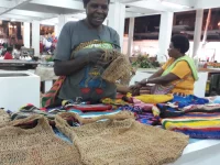 Perajin Papua merajut sekaligus menjual noken, tas rajut tradisional Papua.