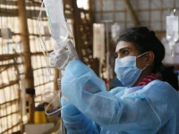 Perawat bermasker menyiapkan kantong infus di klinik bambu kamp pengungsi Rohingya Kutupalong, Bangladesh