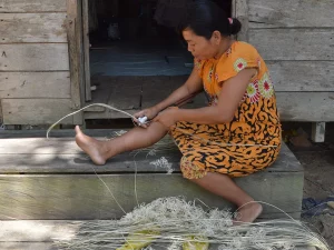 Perempuan Dayak Taboyan meraut rotan di tangga rumah kayu di Desa Baok, Kalimantan Tengah