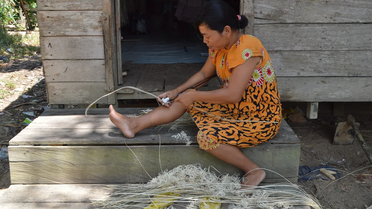 Perempuan Dayak Taboyan meraut rotan di tangga rumah kayu di Desa Baok, Kalimantan Tengah