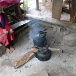 Seorang perempuan lanjut usia menyiapkan kopi di rumahnya di sebuah desa kecil di Thailand.