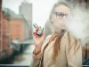 Perempuan menghisap rokok elektrik di luar ruangan