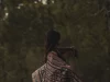 Perempuan berselendang kain tenun Sabu dipotret dari belakang dengan latar pepohonan