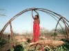 Perempuan Somalia berbaju merah mengikat kerangka kayu rumah tradisional aqal di perdesaan Somalia