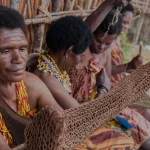 Ilustrasi sejumlah perempuan Papua berkalung untaian manik-manik, yang terdepan memegang noken anyaman kulit kayu