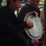 Dua pemain salawat dulang menabuh talam kuningan sambil melagukan syair