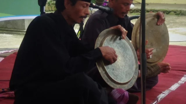 Dua pemain salawat dulang menabuh talam kuningan sambil melagukan syair
