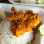 Nasi ayam penyet dengan timun tersaji dalam kotak makanan bawa pulang