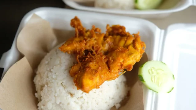 Nasi ayam penyet dengan timun tersaji dalam kotak makanan bawa pulang