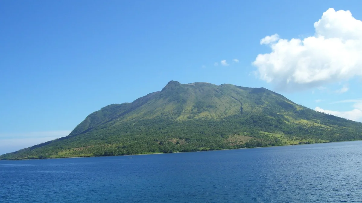 Gunung berhutan di Pulau Sangihe dilihat dari laut di bawah langit biru