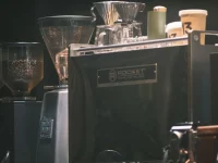 Mesin espreso, penggiling kopi, dan cangkir di meja sebuah kedai kopi