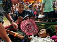 Seorang petugas medis Angkatan Laut Amerika Serikat memeriksa tekanan darah seorang perempuan di Kamboja.
