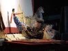 Ilustrasi dalang memainkan wayang di atas panggung pertunjukan.