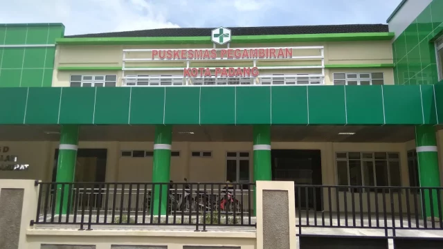 Gedung Puskesmas Pegambiran Kota Padang berdinding hijau dengan pagar besi di depannya