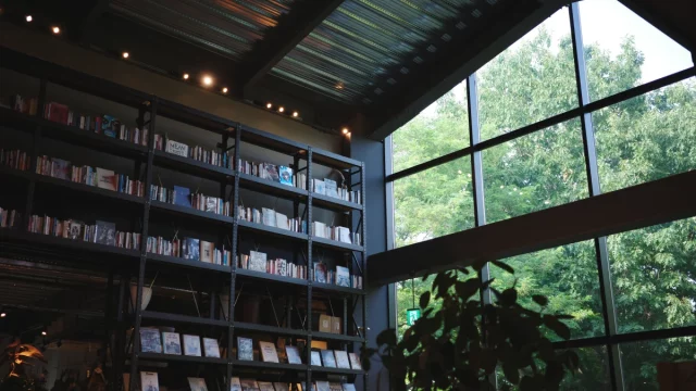 Rak buku bertingkat tinggi berpenerangan hangat di toko buku Tsutaya, Ebetsu, Hokkaido, Jepang