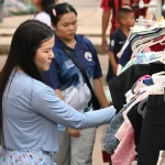 Dua perempuan memilih pakaian di rak gantungan busana sebuah pasar terbuka