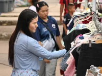Dua perempuan memilih pakaian di rak gantungan busana sebuah pasar terbuka