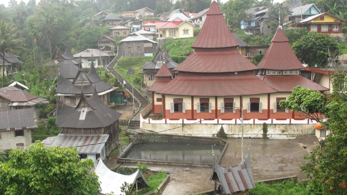 Masjid beratap gonjong merah di Nagari Pariangan dengan kolam di depannya dan rumah-rumah warga di lereng bukit