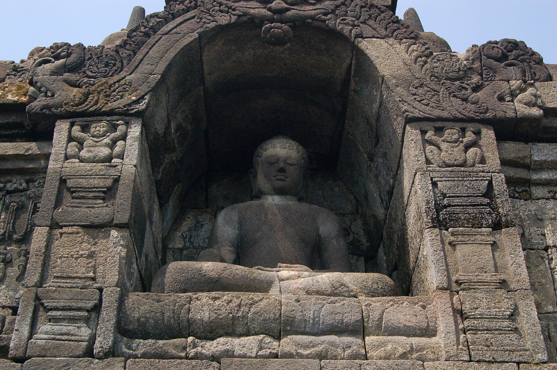 Arca Buddha duduk di dalam ceruk batu di Candi Borobudur.