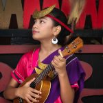 Ilustrasi seorang perempuan berbusana adat memainkan alat musik berdawai.