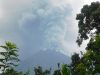 Ilustrasi gunung api menyemburkan kolom abu tebal dilihat dari balik pepohonan.