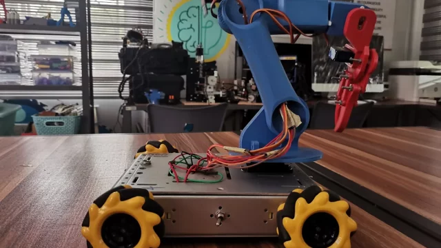 Robot beroda mekanum berlengan di atas meja kerja laboratorium